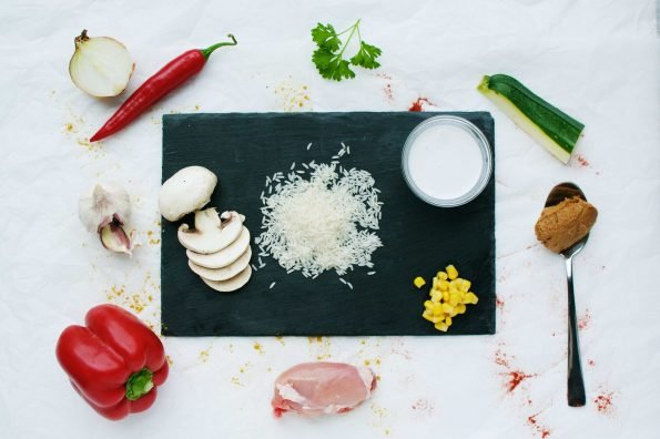 Foto met ingredienten peper knoflook paprika pindakaas rijst courgette kip kokosmelk champignons